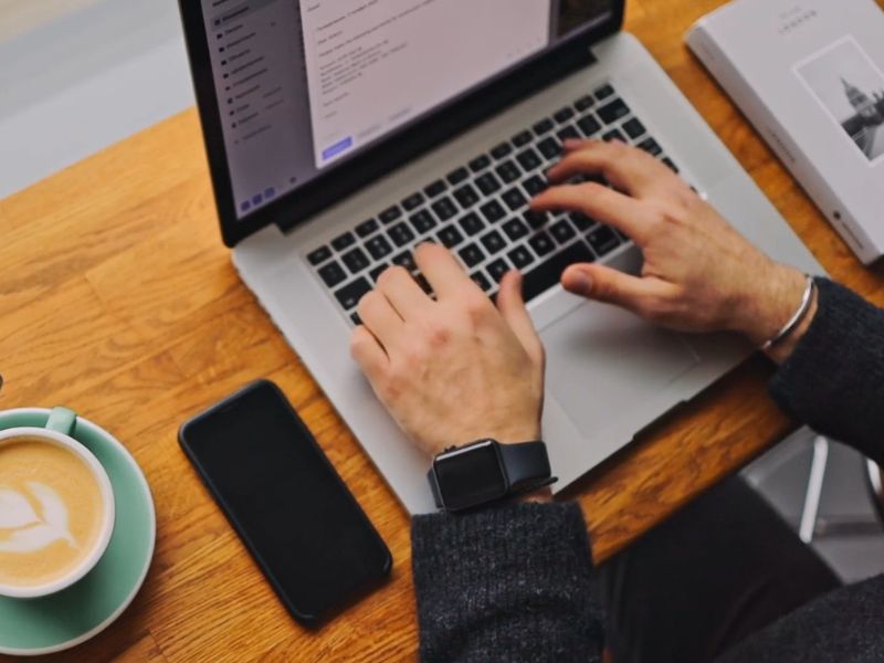 momak piše na laptopu blog uz kafu