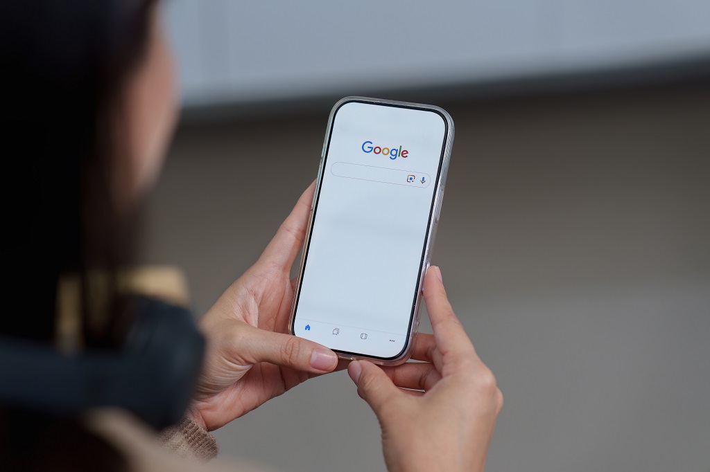 Osoba pretražuje Google na mobilnom telefonu, kao simbol borbe za vidljivost sajta u rezultatima pretrage