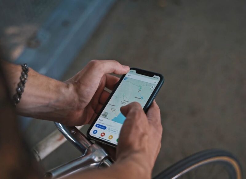 osoba sedi na biciklu i koristi mapu preko telefona