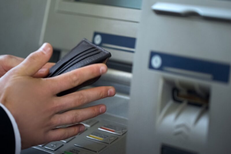 prikaz bankomata i osobe koja drži novčanik u ruci