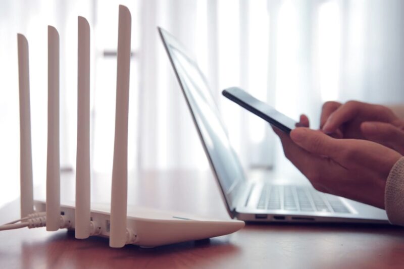 prikaz rutera laptopa i osobe koja koristi telefon