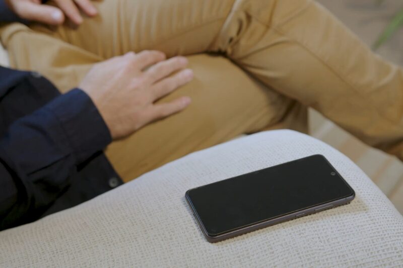 prikaz osobe koja sedi na ugaonoj i telefona pored nje