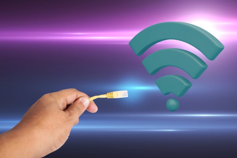 osoba drži wifi kablić u ruci, pored wifi signal
