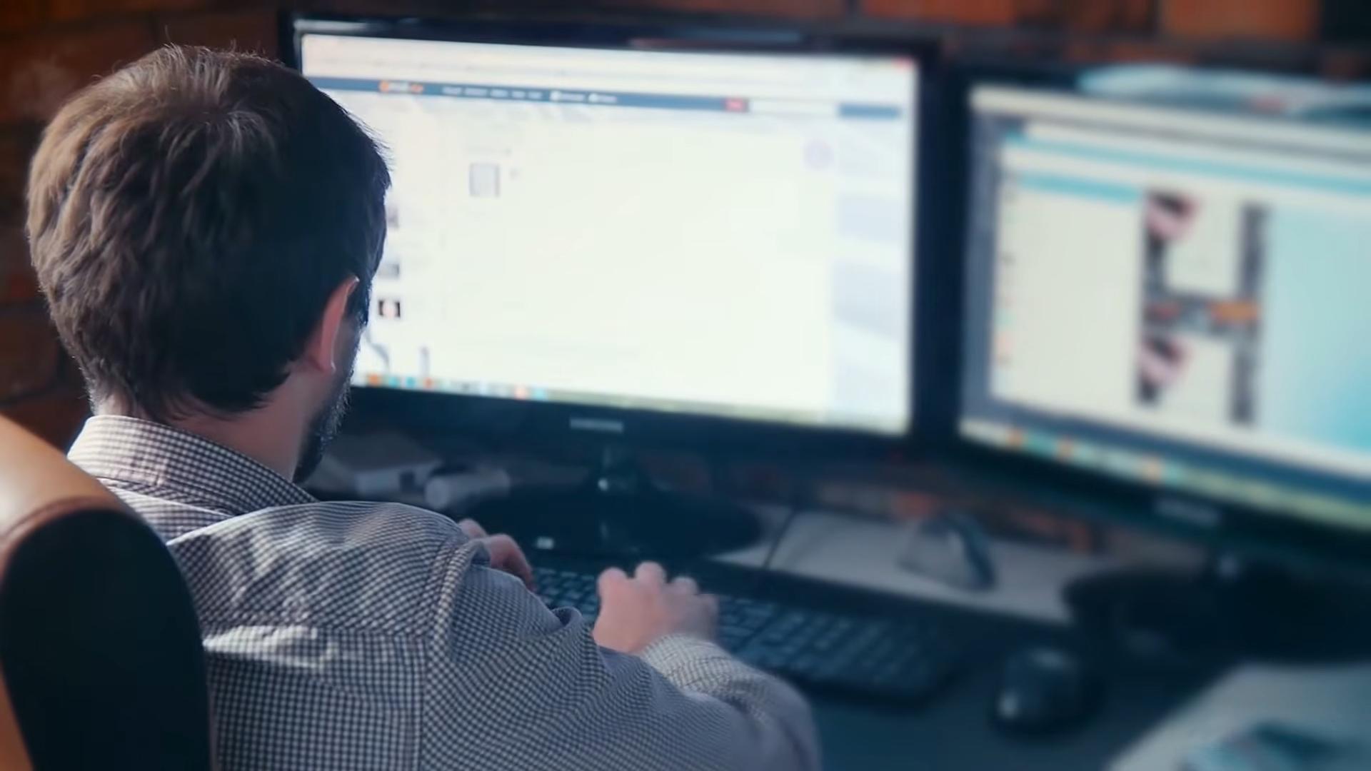 Muškarac radi za računarom sa dva monitora